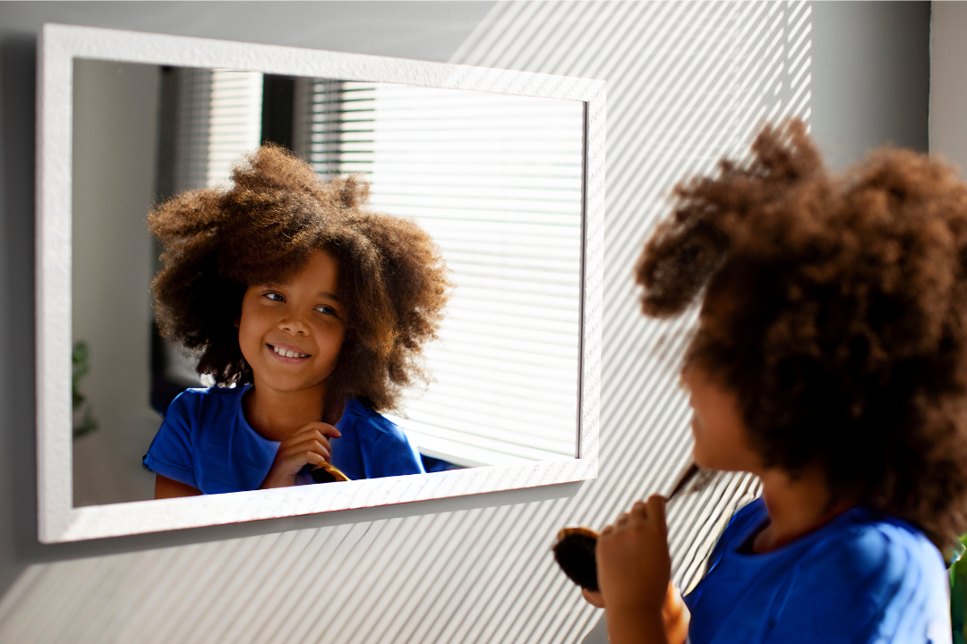 Menina se olhando no espelho. Inglês e Autoestima Infantil: tudo o que você precisa saber! Foto Reprodução: Freepik