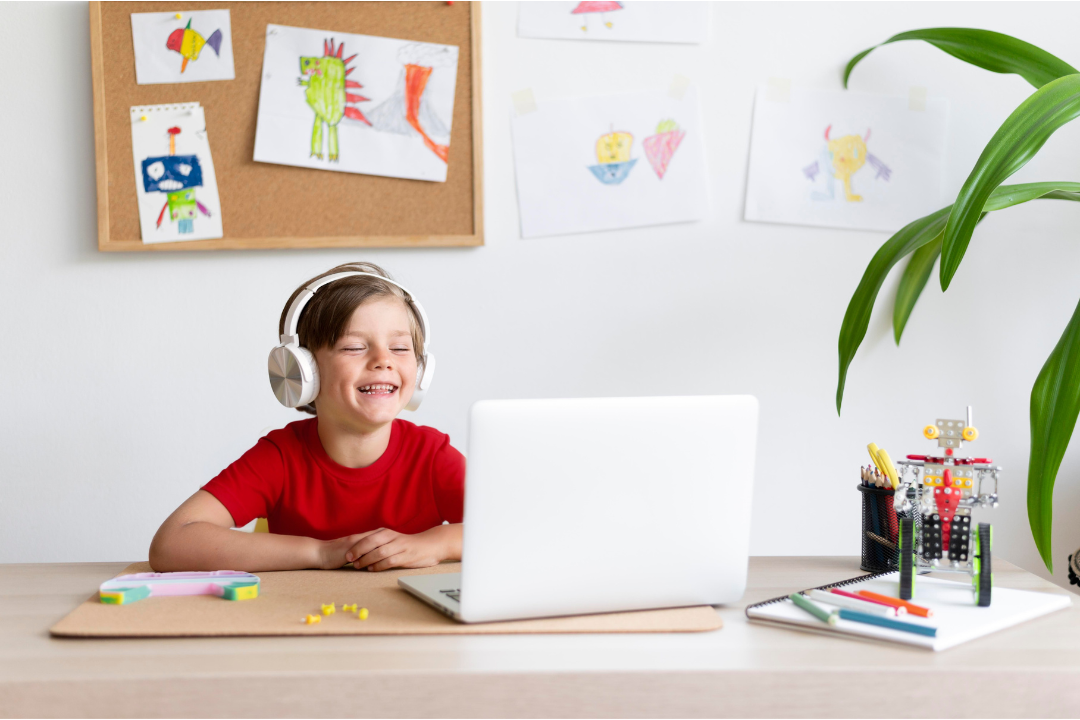 Menino feliz assistindo aula online. Como funcionam as aulas em turma no Kidsa? Foto Reprodução: Freepik.