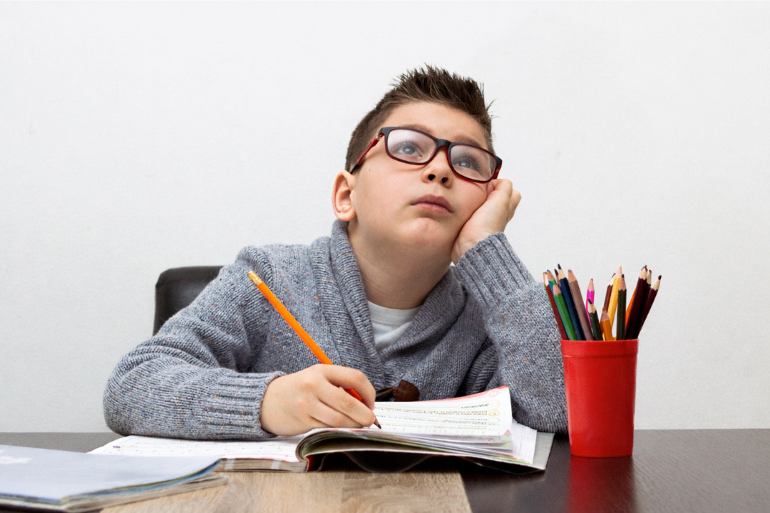 Menino entendiado ao estudar. Como evitar que a criança perca o interesse em aprender inglês? Foto/Reprodução: Freepik.