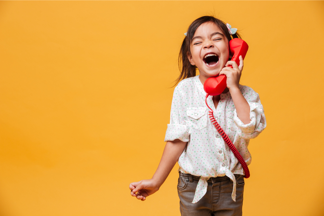 Menina feliz falando ao telefone. Inglês na infância ajuda no desenvolvimento da comunicação? Foto/Reprodução: Freepik.