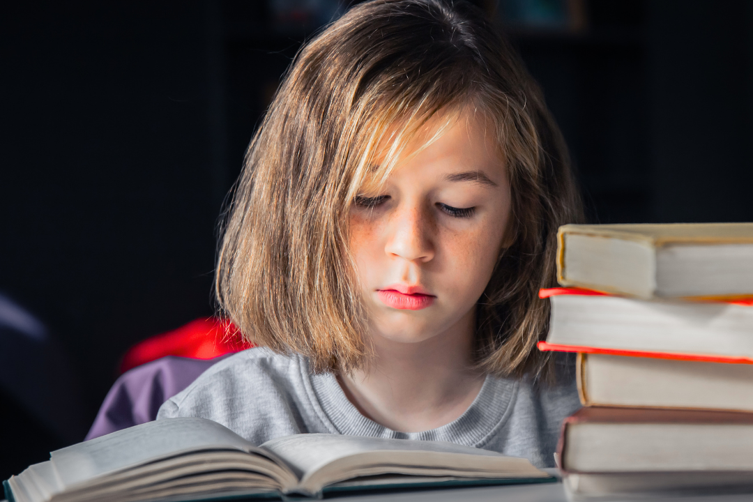 Menina desanimada lendo um livro. Por que algumas palavras em inglês são mais fáceis de aprender? Foto/Reprodução: Freepik.
