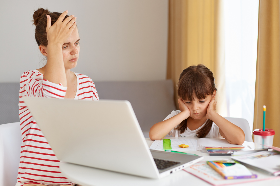 Mãe cansada ajudando filha com o dever de casa. Maternidade real: como encaixar o inglês na rotina (sem surtar!) Foto/Reprodução: Freepik.