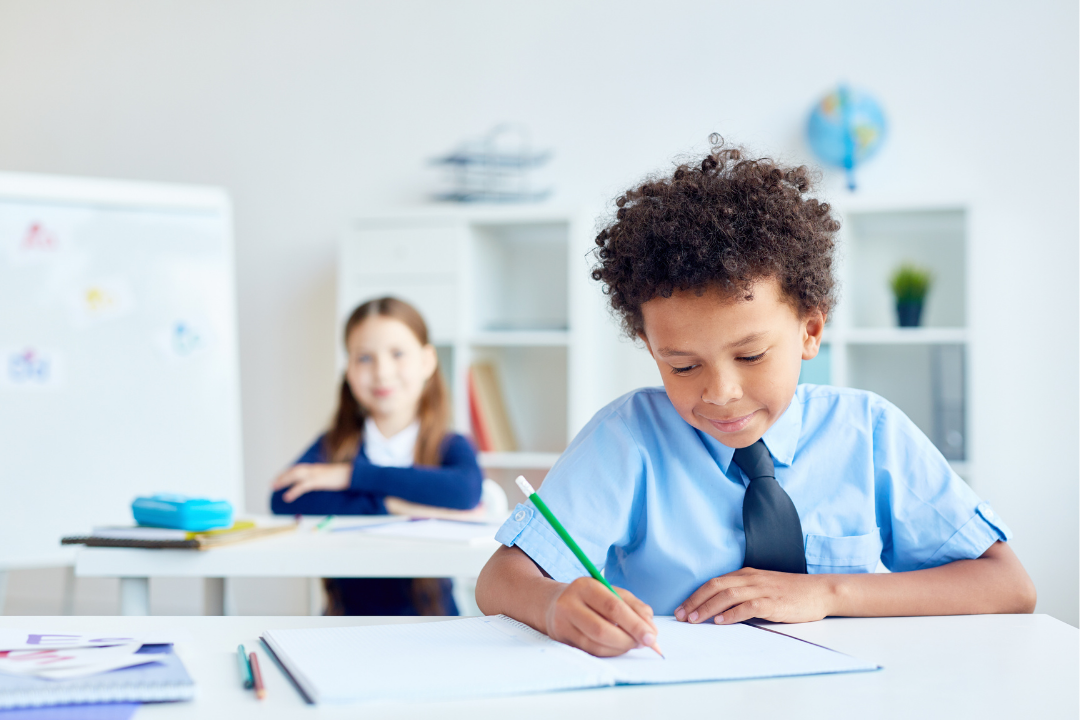 Menino em sala de aula realizando atividade. Como o inglês pode melhorar o desempenho escolar da criança? Foto/Reprodução: Freepik.