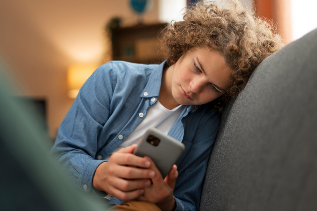 Adolescente entediado usando o celular. Por que adolescentes perdem o foco: entenda as causas e como ajudar. Foto/Reprodução: Freepik.