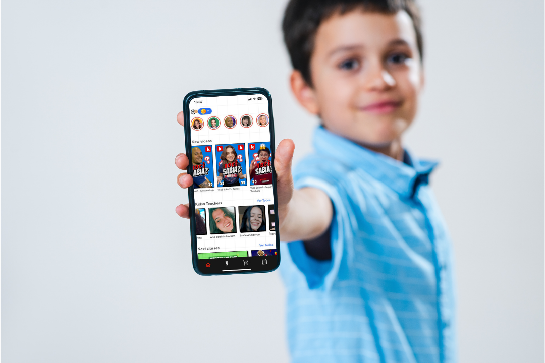Menino segurando um smartphone. Por que o Kidsa App é o reforço ideal para crianças? Foto/Reprodução: Freepik e Canva.